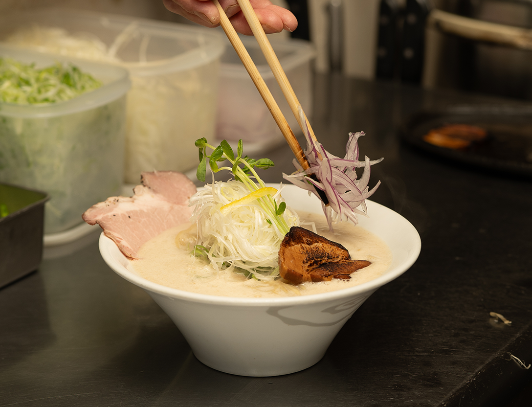 画像：鍋をかき混ぜているラーメン甚八スタッフの写真